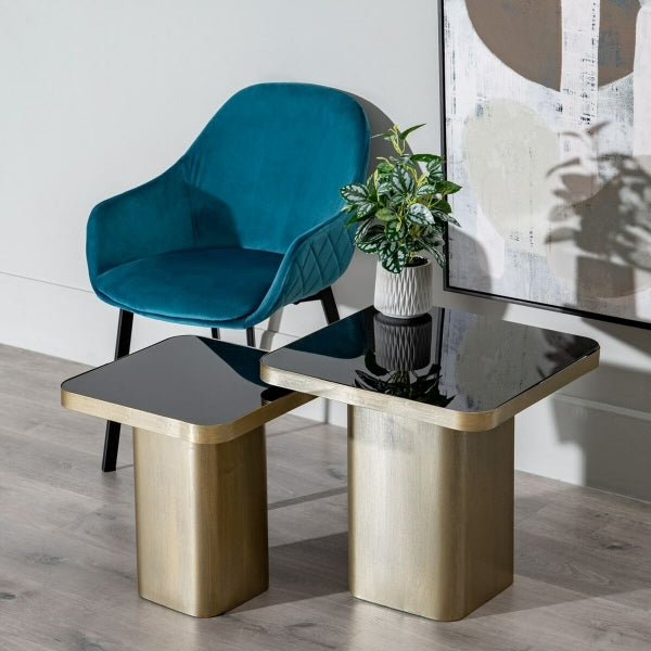 Petite Table d'Appoint Design en Verre Noir et Métal Doré dans un salon contemporain avec un fauteuil bleu dans le fond de la pièce